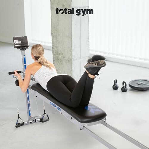 Person exercising on Total Gym Apex G3 with weights in the background.